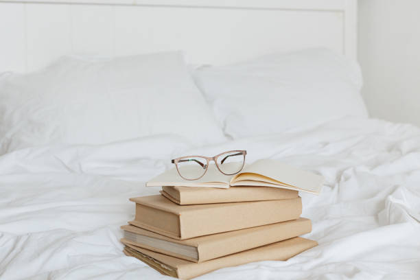 istock Books on bed white bed linen. 1205809591