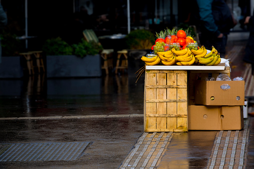 Street stall selling various types of fruit on boxes on a street in Paris