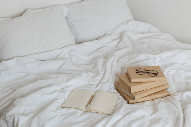 istock Books on bed white bed linen. 1205810305
