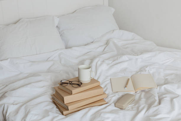 istock Books on bed white bed linen. 1205810369