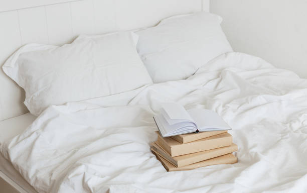 istock Books on bed white bed linen. 1205810474