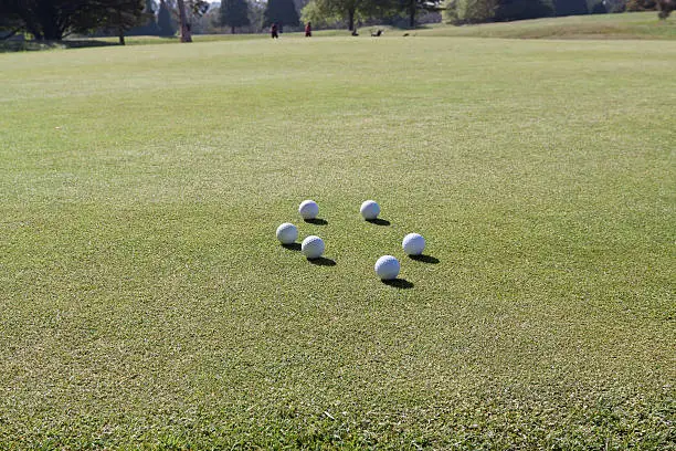 White Golfballs on green grass of golf course, full frame horizontal composition