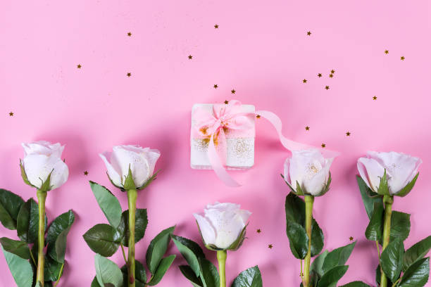 istock Pink rose and white gift box with pink ribbon on pink background 1205812451
