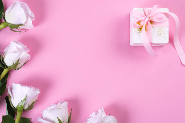 istock Pink rose and white gift box with pink ribbon on pink background 1205812769