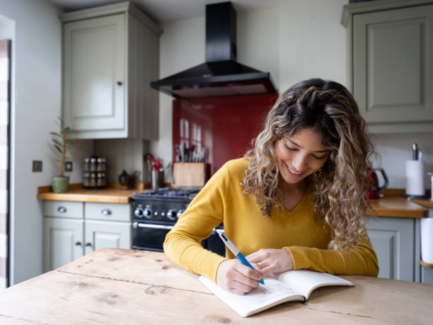 istock Latin american happy woman at home writing on her notepad smiling 1205813687