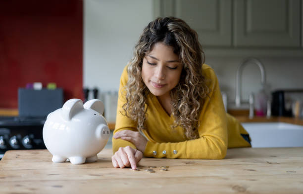 istock Thoughtful young woman counting her coins on the kitchen counter 1205813752