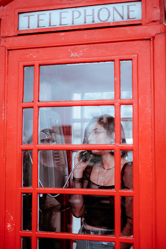 portrait of a young woman in red telephone box