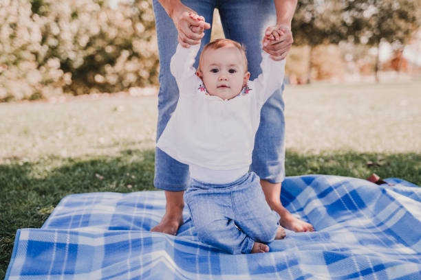 jeune mère jouant avec la petite fille à l’extérieur dans un stationnement, concept heureux de famille. fille mère d’amour. en regardant la caméra, les premiers pas de bébé - baby first steps autumn child photos et images de collection