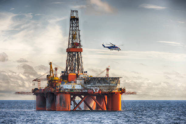 Chopper landing on a oil rig at day stock photo