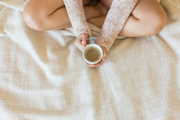 istock Young woman enjoying her coffee while sitting in bed. Top view. 1205832965