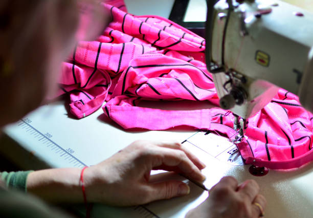 istock Sewing process - women's hands on the background of a sewing machine while sewing clothes from fabric 1205834067