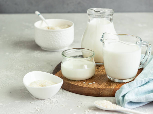 istock Rice milk in jugs and rice in a white ceramic bowls and spoon on a light grey stone background. Alternative type of milk. Vegan substitute dairy milk. 1205836274