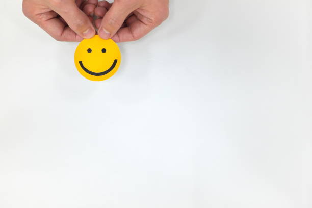 istock Human hands holding a yellow smiley face on a white background. Positive feedback, satisfied customer and good service concepts 1205836845