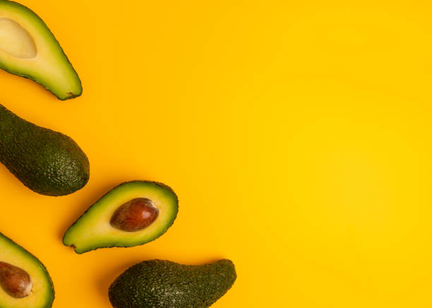 istock Ripe juicy halved  avocado on a yellow solid background with copy space. 1205837523