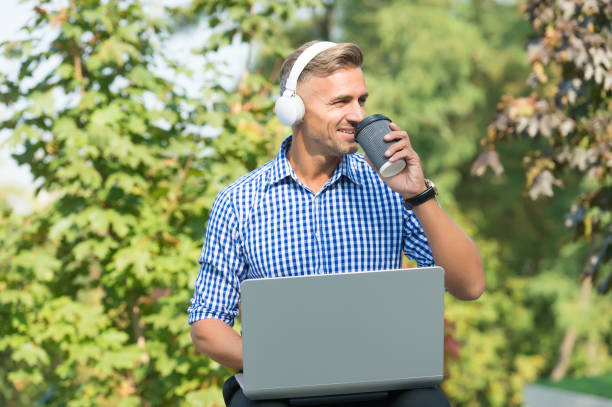 istock Podcast business development. Podcast for manager. Musical service. Handsome man listening podcast while work with laptop. Always studying. Online communication. Personal blog social networks 1205838093