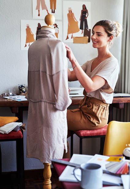 Being a perfectionist is part of the job Shot of a young fashion designer working on a garment hanging over a mannequin fashion designer stock pictures, royalty-free photos & images