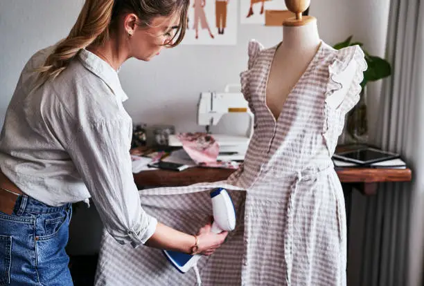 Shot of a fashion designer using  a garment steamer in her workshop
