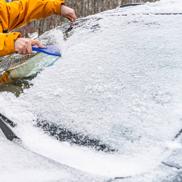 istock Man's hands cleaning a car from the snow and ice after a snowfall 1205839473