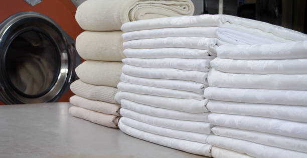 istock Stack of folded white cloths in an industrial laundry. Cleaning and service concept. 1205839564