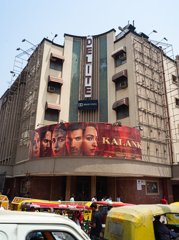 Façade of the Delite Theatre, with an advertising of a movie, a chaotic street in the foreground.\nDelhi, India.
