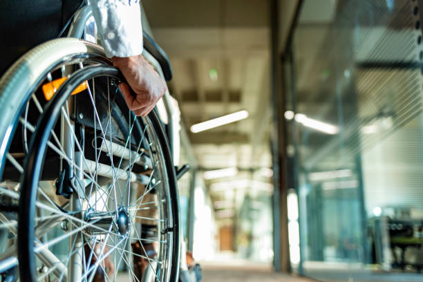 Back view of unrecognizable person in a wheelchair in a hallway stock photo