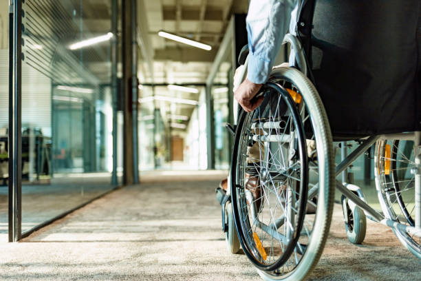 Wheeling his way into recovery Paralyzed man in a wheelchair on the move in the disabled office building. disability photos stock pictures, royalty-free photos & images