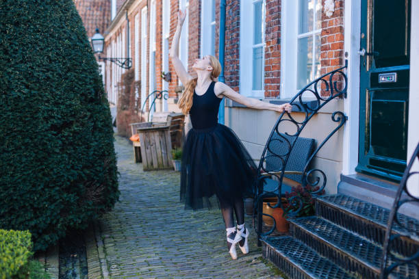 la jeune femme de ballerine avec le cheveu rouge dans le costume de ballet et les chaussures de pointe est dans la belle danse de pose sur la rue. - dancing ballet one person en pointe photos et images de collection