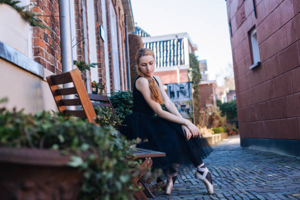 la jeune femme de ballerine avec le cheveu rouge dans le costume de ballet et les chaussures de pointe est dans la belle danse de pose sur la rue. - dancing ballet one person en pointe photos et images de collection