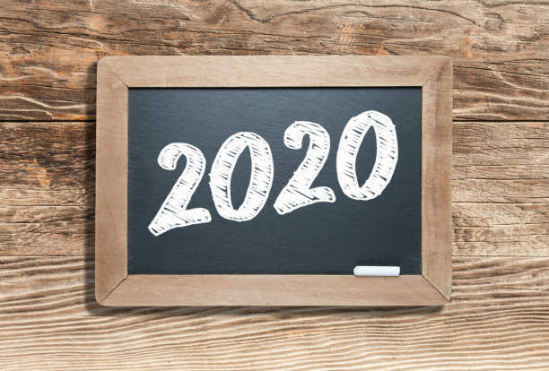 istock 2020 Written on Slate Chalk Board Against Aged Wood Background 1205846009
