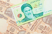 eine-iranische-zehntausend-rial-banknote-auf-einem-bett-von-indischen-zehn-rupien-banknoten.jpg?b=1&s=170x170&k=20&c=Kbc_O5s3Ou4NX2UzNoaZide4-A5_vwt60-TzbPVNv2o=