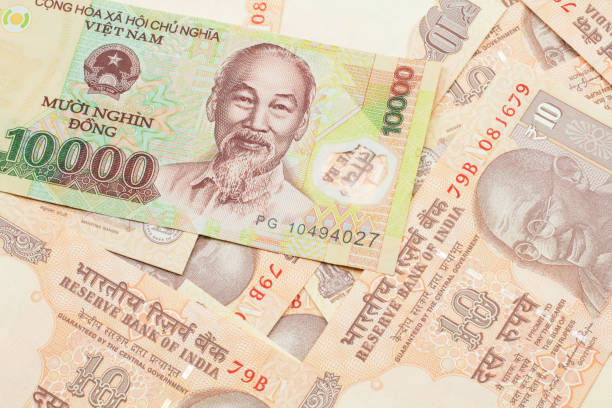 A Vietnamese dong bank note with Indian ten rupee bank notes stock photo