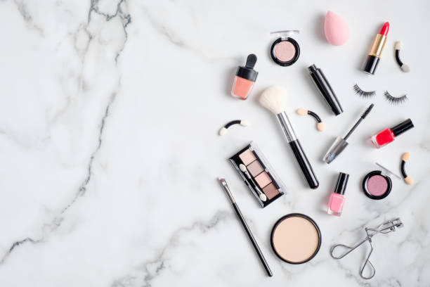 istock Makeup cosmetic products spilling out on to a white marble background. Flat lay, view from above. Beauty salon banner design template 1205849640