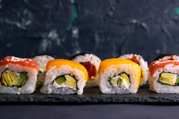 istock Different types of rolls stand on a black granite board for sushi on a black background 1205850765
