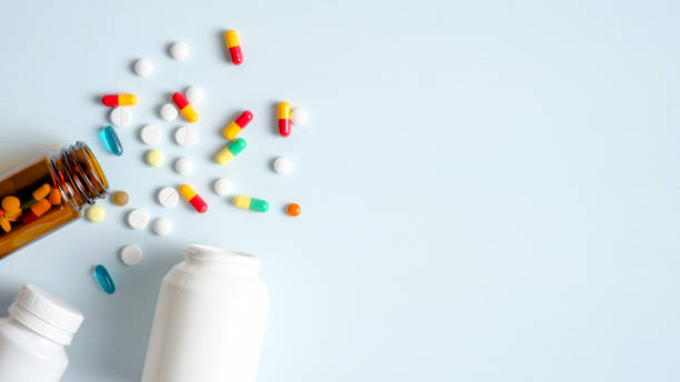 bouteilles médicales et pilules de médicaments déversant sur le fond bleu pastel. vue du haut avec l’espace de copie. soins de santé, pharmacie, concept de médecine - prescription medicine pill medicine bottle photos et images de collection