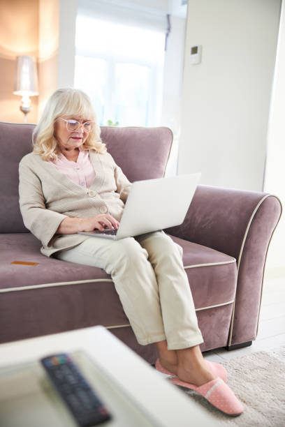 istock Smiling elderly woman using laptop at home 1205850907