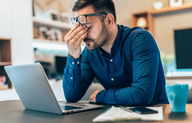 Home office Tired young businessman working at home using lap top and looking Anxious overworked stock pictures, royalty-free photos & images