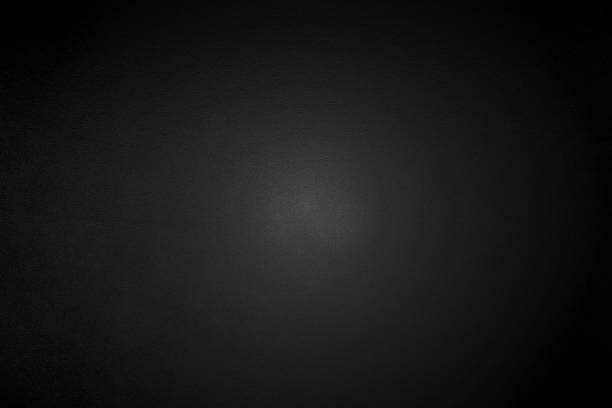 istock Light shining down on black metal wall in dark room with copy space, abstract background 1205863717