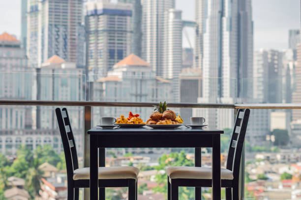 завтрак с кофейными фруктами и хлебным круазантом на балконе на фоне большого города - scenics building exterior tourist resort orange стоковые фото и изображения