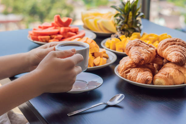 une jeune femme déjeune sur le balcon. table de petit déjeuner avec le café et le croisant de pain sur un balcon sur le fond de la grande ville - 3503 photos et images de collection