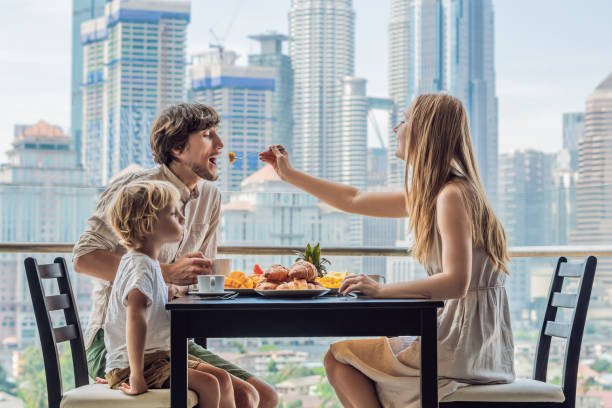 famille heureuse ayant le petit déjeuner sur le balcon. table de petit déjeuner avec le café et le croisant de pain sur un balcon sur le fond de la grande ville - 3518 photos et images de collection