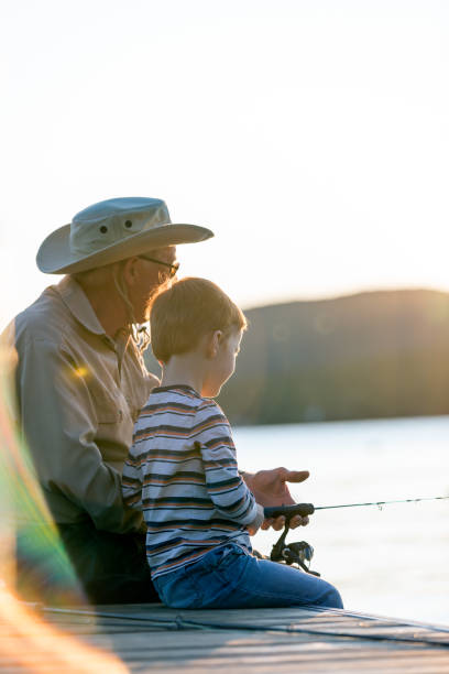 avô e neto pescando ao pôr do sol no verão - fishing lake grandfather grandson - fotografias e filmes do acervo