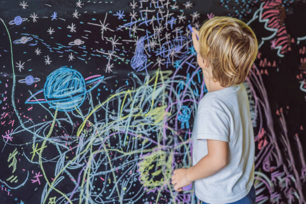 istock Little boy pointing space, planets and stars on the wall 1205870357