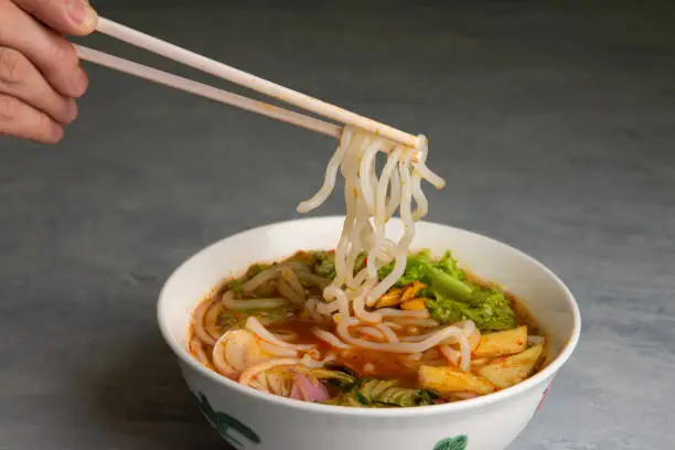 hand with chopstick and laksa curry noodles