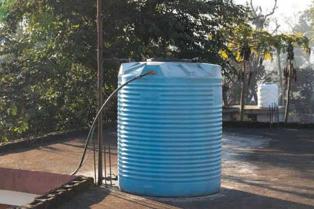 Photo of Blue water tank placed on the terrace of house connected with steel pipes.