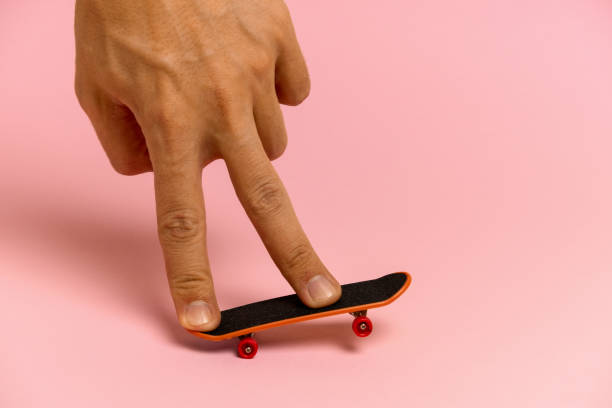 hand of a young man on a mini skateboard hand of a young man on a mini skateboard on a pink background wasting time stock pictures, royalty-free photos & images