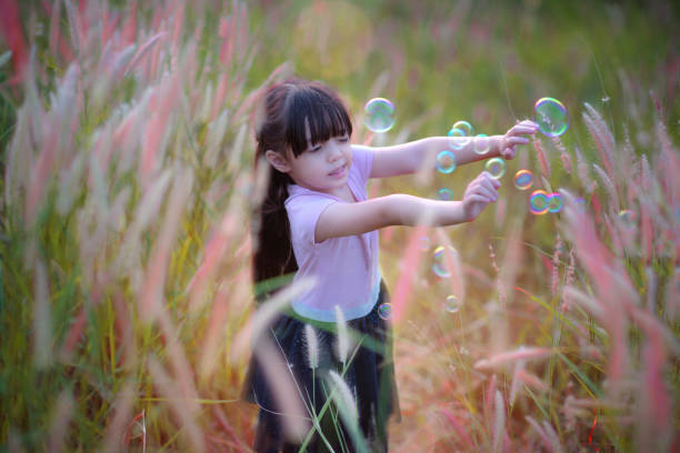 kid girl scare of the bubble floating in the air, girl playing bubble on meadow of hill