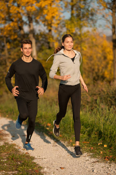 istock Young  veautiful couple runs on a path in park on autumn afternoon 1205897099