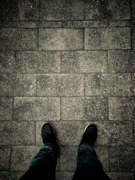 istock Close up human feet standing on the road. The ground is paved with bricks. 1205897245