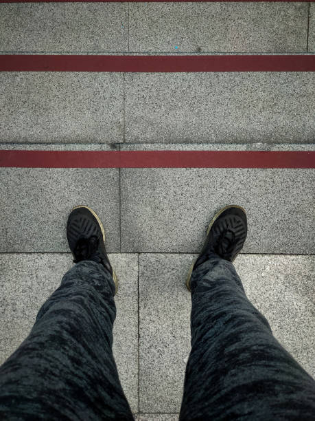 istock Closeup human feet standing on stairs. Going down. 1205897326