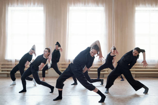 Contemporary Dance Team Rehearsal Team of contemporary dancers working on new dance moves together in their rehearsal studio, horizontal shot contemporary dance stock pictures, royalty-free photos & images